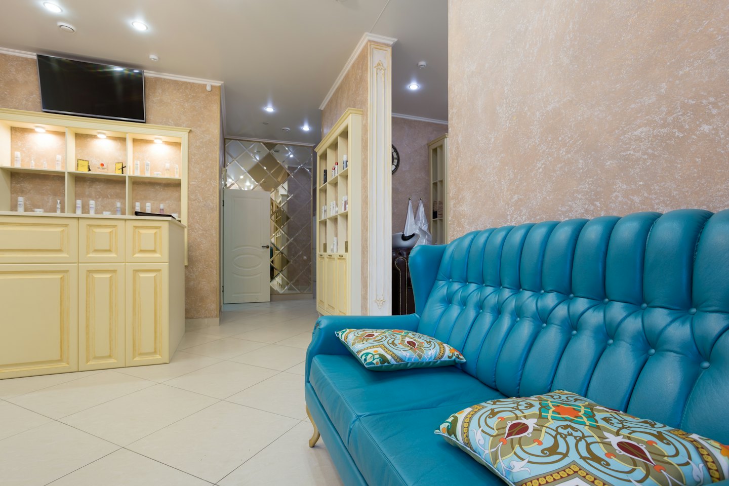 Canapé touffeté turquoise avec coussins décoratifs dans un espace d'attente de salon.