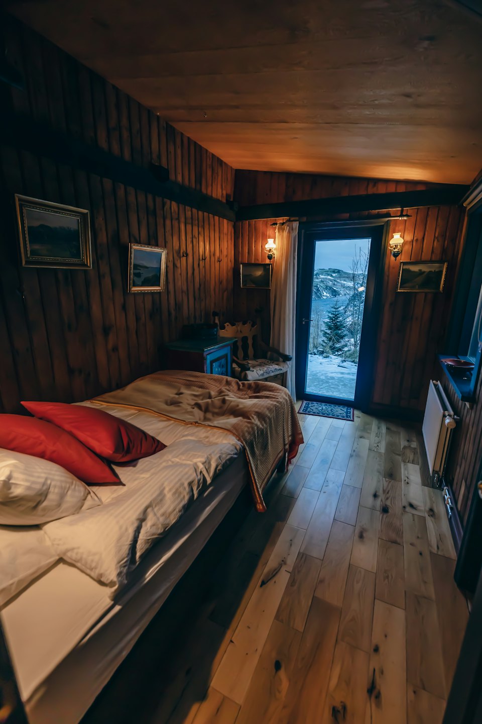 Une chambre rustique avec du linge blanc donne sur un paysage enneigé.