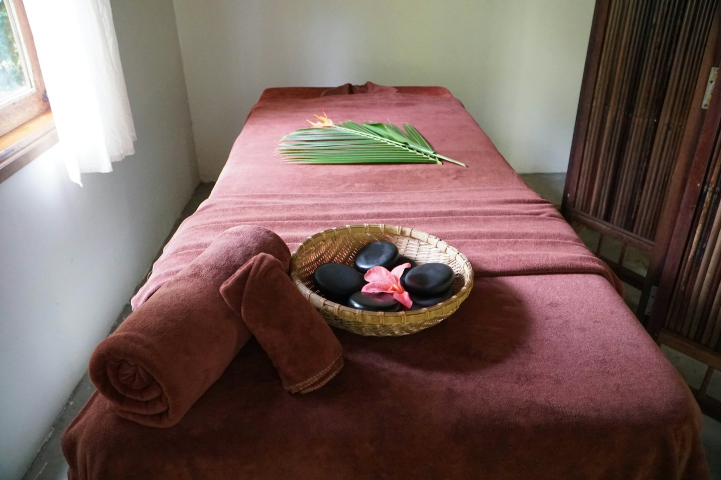 Table de massage avec serviettes et pierres dans une salle de spa.